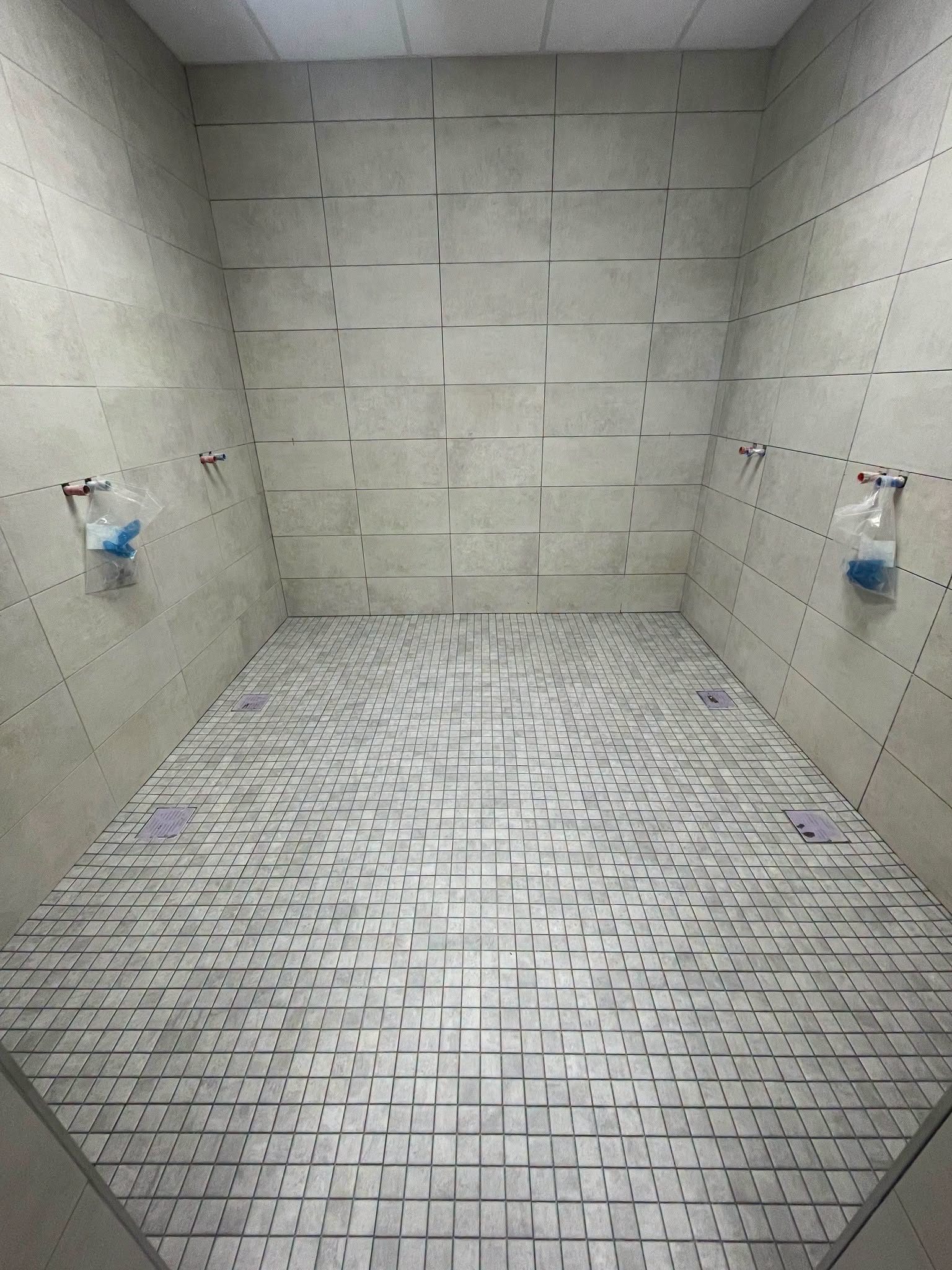 Fertig gefliester Duschraum mit Mosaikboden, bereit für die Sanitärinstallation