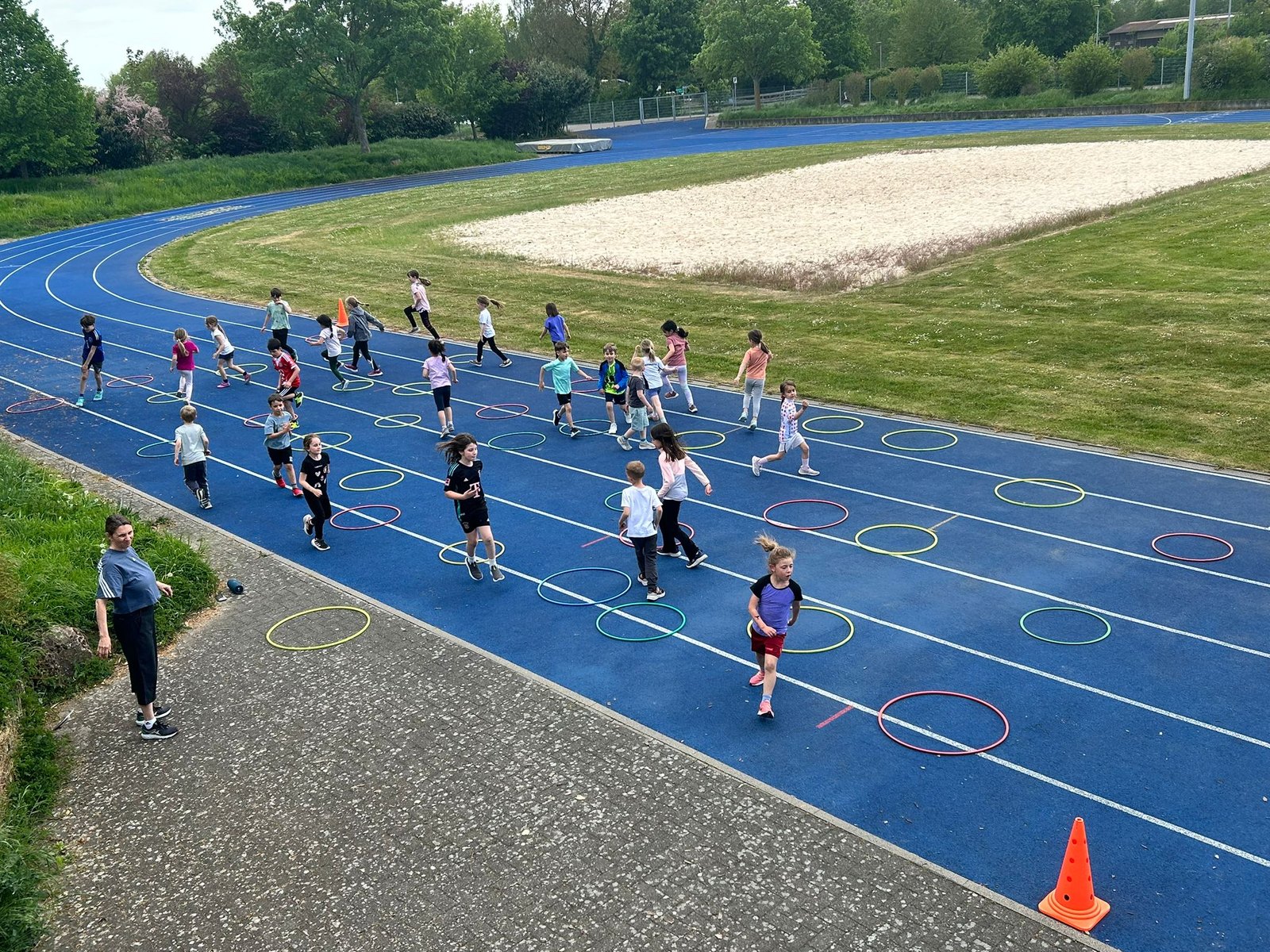 Kinder beim Koordinationstraining mit bunten Reifen auf der blauen Laufbahn des TSV 1905 Rot